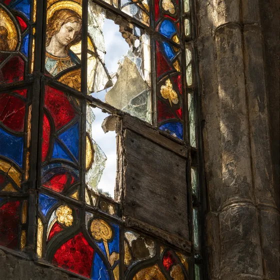 Damaged historic stained glass church window with cracked panes