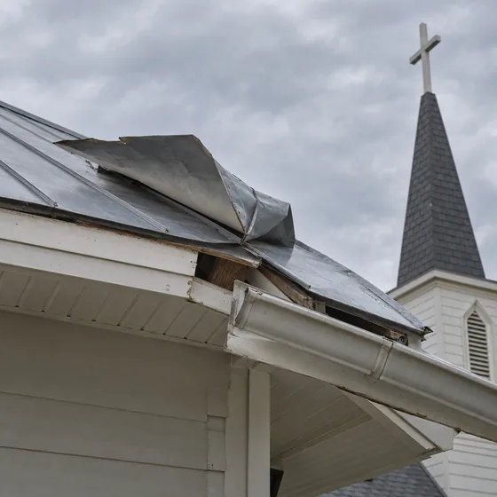 Wind damage peeling metal flashing from church roof edge