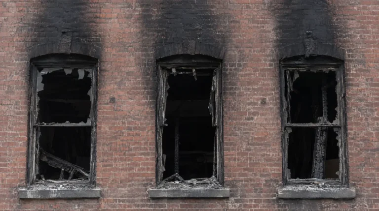 Smoke and soot staining a brick commercial building facade after a fire damage insurance claim